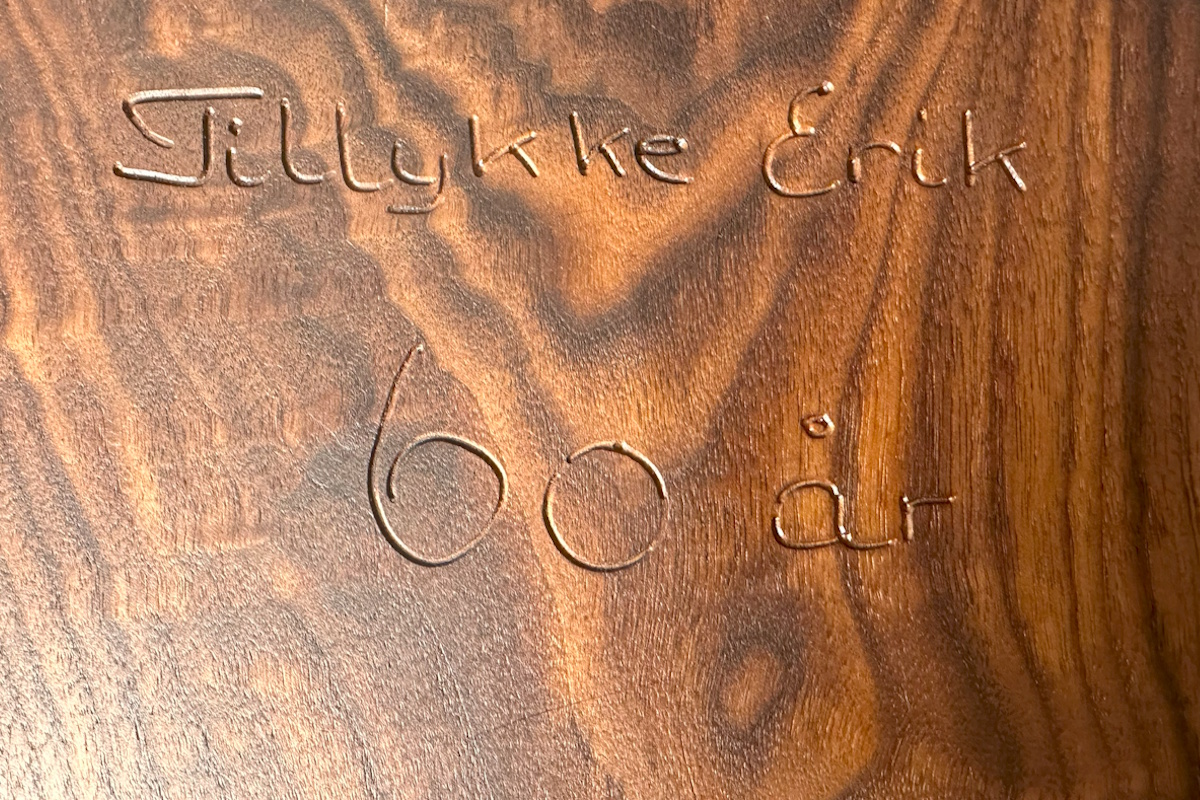 Tekstindgravering i træ, detaljeret håndværk og elegant dekorativ finish.